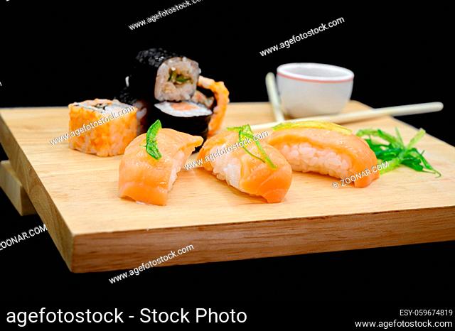 Close Up Of Various Types Of Japanese Fresh Prepared Sushi on wooden table on black isolated background