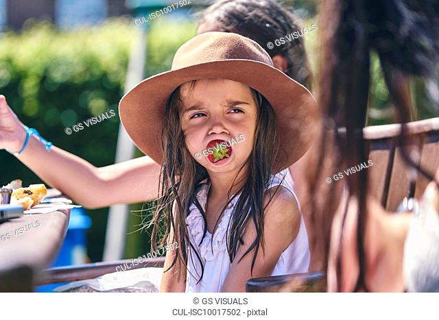 Girl daydreaming with strawberry in mouth