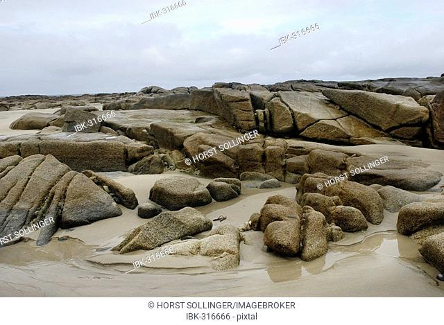 Granite rocks in tidal zone of sandy beach at the Altanic coast of Donegal on a foggy day, Ireland