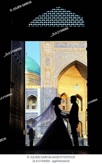 Wedding photography, silhouettes of bride and groom in front of the Mir-i-Arab Madrasa. Uzbekistan, Bukhara