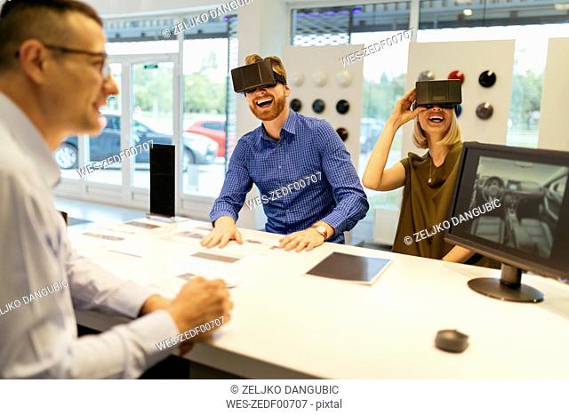 Couple using VR glasses in car dealership