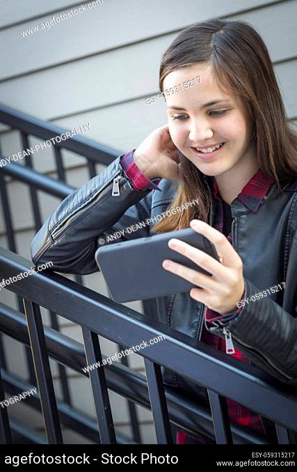 Pretty Smiling Young Girl on Staircase Looking at Smart Phone