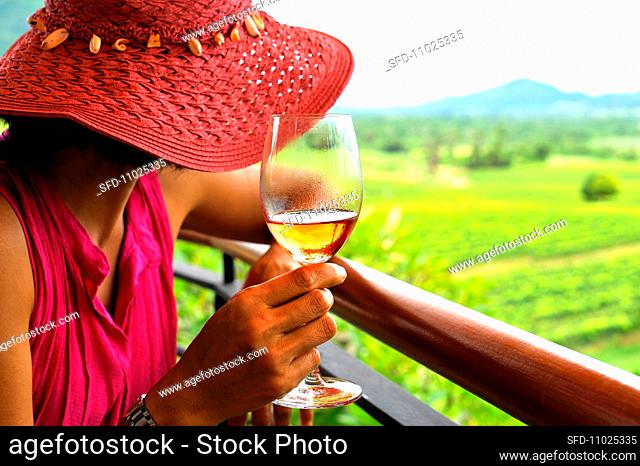 A woman with a glass of rose surveying a vineyard