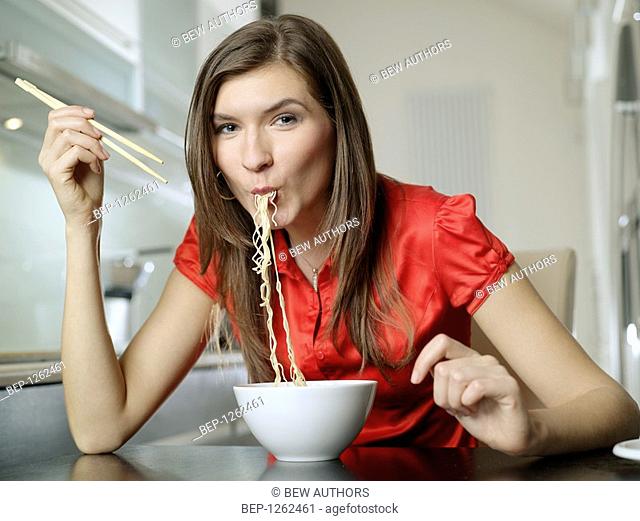 Woman eating chinese soup with noodles