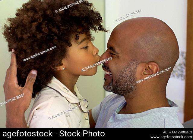 Daughter kissing his father's nose and looking at each other