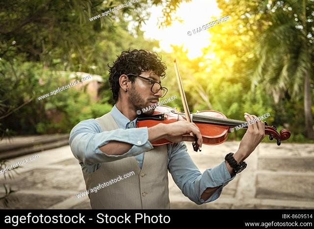 Portrait of man playing violin at sunset. Close up of violinist man playing in the street. Violinist artist playing a melody outdoors