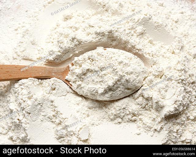 white wheat flour in a wooden spoon, top view, close up