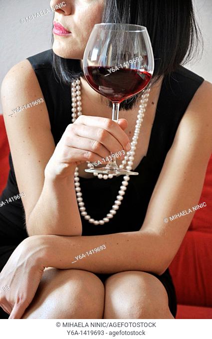 Young woman holding glass of red vine