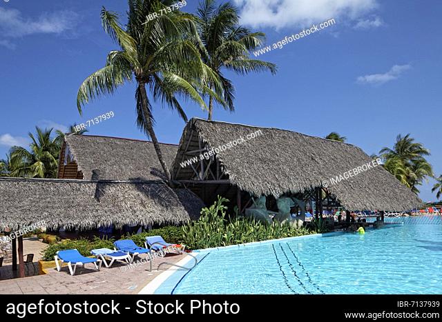 Pool, pool bar with palm leaf roof, sun loungers, coconut palms (Cocos nusifera) Hotel Brisas, Playa St. Lucia, Camagüey Province, Caribbean, Cuba