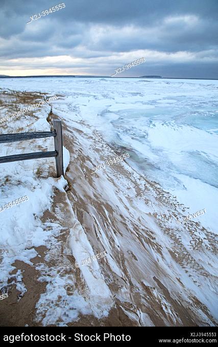Au Train, Michigan - Lake Superior in the winter. A fence guarding a walkway to the beach ends abruptly where the shoreline has been eroded
