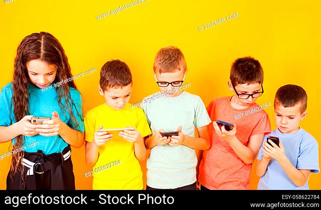 Group of kids using digital mobile phone over yellow background