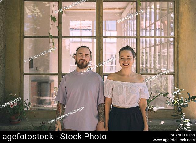 Smiling boyfriend and girlfriend standing in front of window