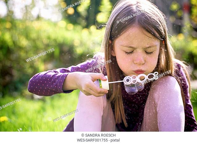 Girl blowing soap bubbles in a garden