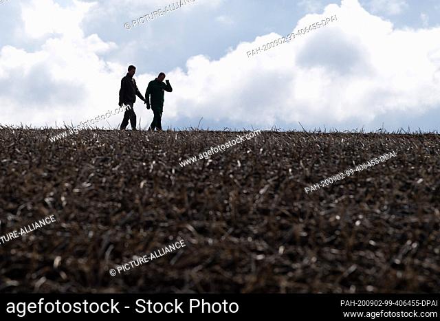 02 September 2020, Saxony, Zwönitz: Two farmers are walking with a bucket over a potato field on the fringes of a press conference on the harvest balance of the...