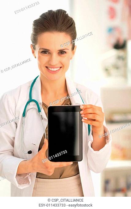 Happy medical doctor woman showing tablet pc blank screen