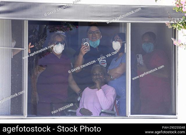 Health care workers and patients watch from a window as US Vice President Kamala Harris enters the Los Angeles County Federation of Labor, AFL-CIO