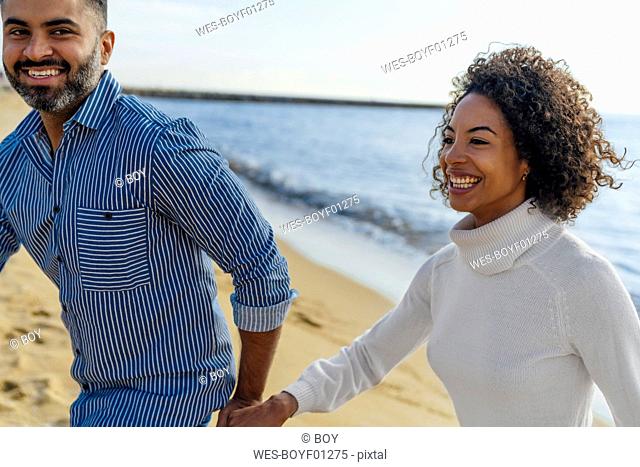 Spain, Barcelona, happy couple having fun on the beach