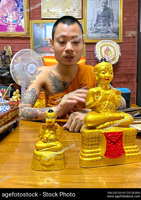 23 June 2020, Thailand, -: Phra Anuchit Upanan, a monk in Wat Samngam temple, shows Kuman Thong figures. These are baby figures
