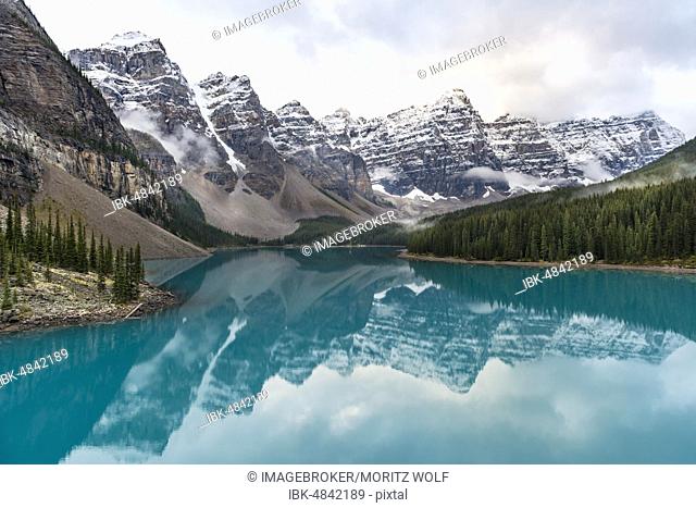 Clouds hanging between mountain peaks, reflection in turquoise glacial lake, Moraine Lake, Valley of the Ten Peaks, Rocky Mountains, Banff National Park