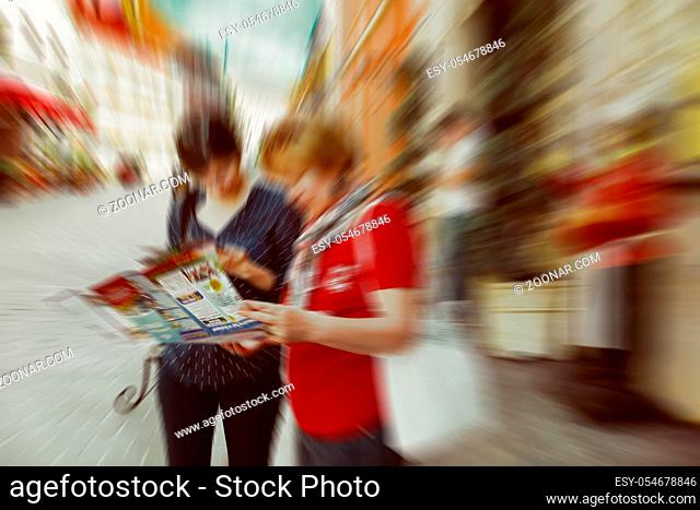 Abstract background. Two tourists looking map of Budapest - radial zoom blur effect defocusing filter applied, with vintage instagram look