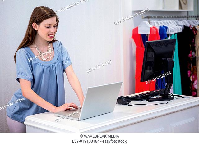 Shop worker using laptop by the till