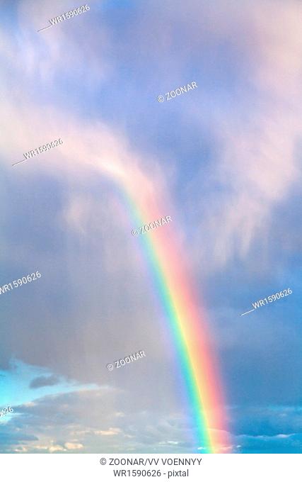 rainbow in blue cloudy autumn sky