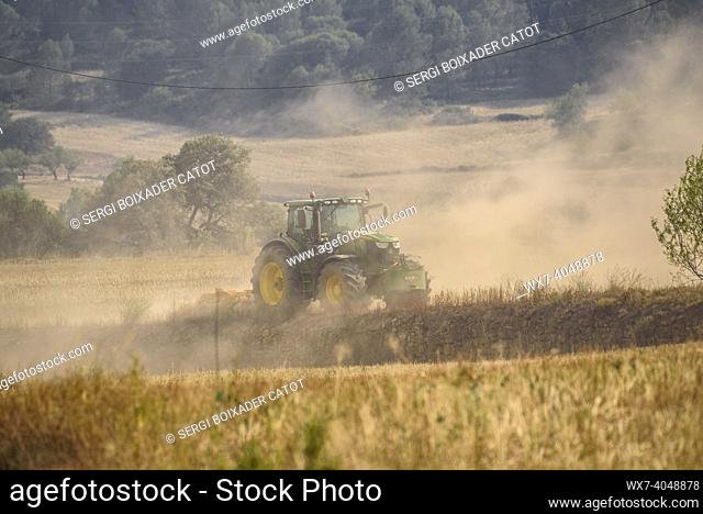 Tractor working to prevent the advance of the 2022 Pont de Vilomara wildfire with a cloud of dust due to extreme drought (Bages, Barcelona, Catalonia, Spain)