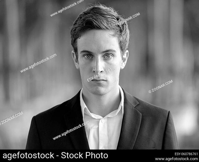 Portrait of young handsome businessman in suit at the airport outdoors in black and white