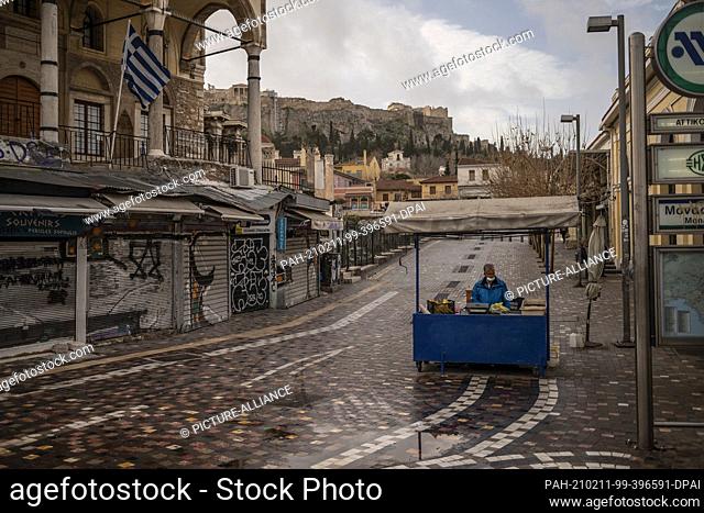 11 February 2021, Greece, Athen: A fruit vendor waits for customers at the empty Monastiraki Square below the Acropolis.
