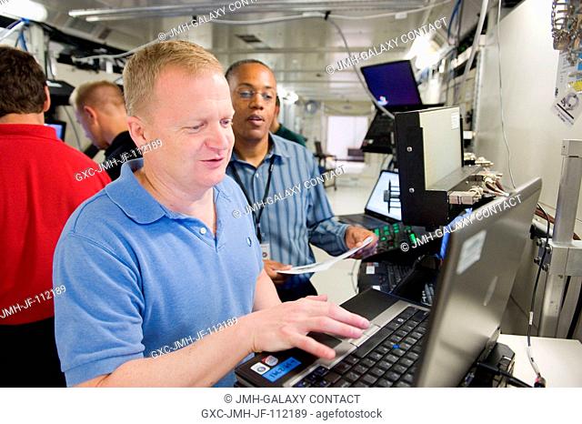 NASA astronauts Eric Boe (foreground), STS-133 pilot; and Alvin Drew, mission specialist, participate in a robotics training session in the Jake Garn Simulation...