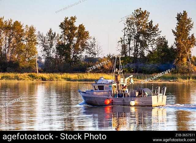 Commercial fishing vessel retuning to harbour at sunset in Steveston British Columbia Canada