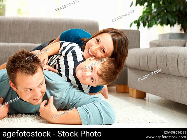 Happy family playing at home, lying heaped on floor in living room