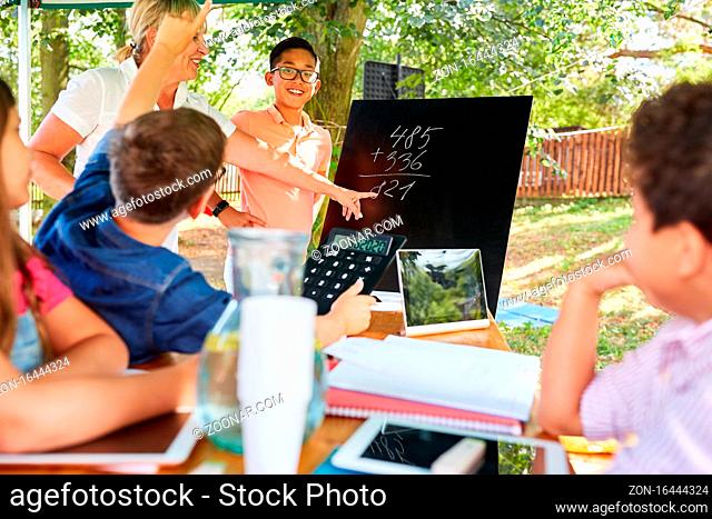 Kinder lernen Rechnen an der Kreidetafel im Nachhilfe Ferienkurs der Sommerschule