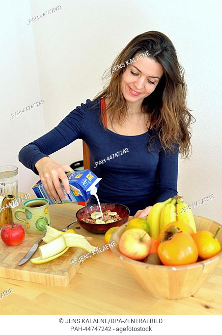 A young woman pours milk over cereals in a bowl in Berlin, Germany, 02 December 2013. Photo: Jens Kalaene - MODEL RELEASED | usage worldwide