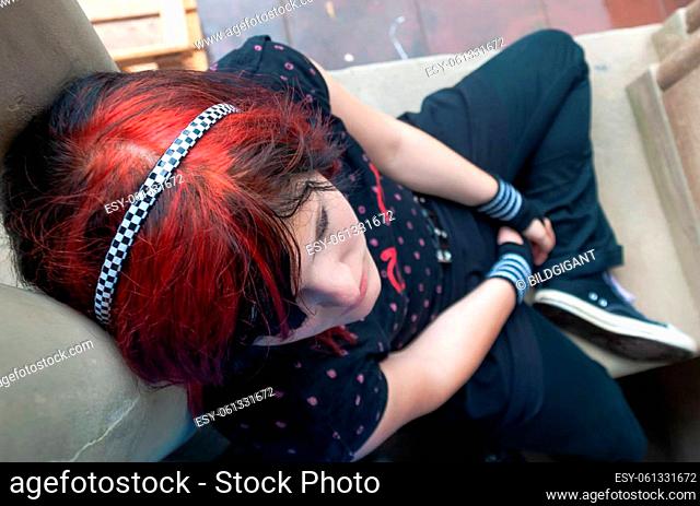 Punk emo girl, young adult with black red hair, sitting at a window frame, looking up, high angle view, horizontal