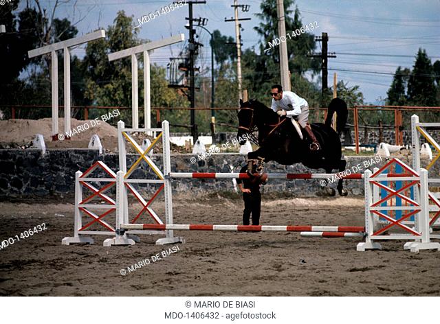 Raimondo D'Inzeo, a Carabinieri Official, jumps over an obstacle during a training session; the horse jockey trains at the Lopez Mateos military riding school