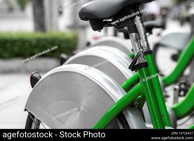 Street transportation green hybrid rent bicycles with electronic form of payment for traveling around the city stand in row