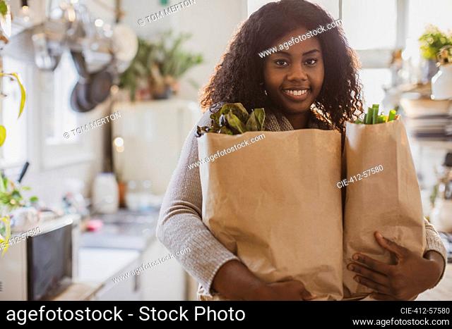 Portrait young woman with groceries in kitchen