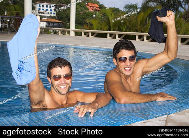 Men removing swim trunks in swimming pool