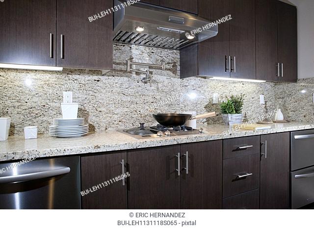 Kitchen having brown cabinets with granite counter top and wall at home; Irvine; California; USA