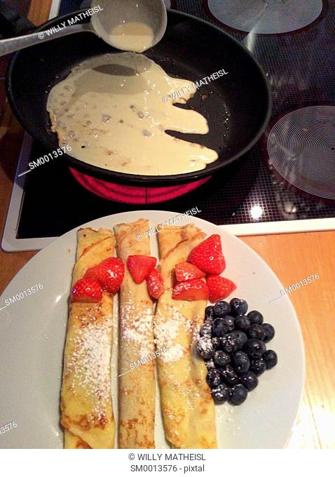Homemade Bavarian pancakes with strawberries, sugar powder and fresh blueberries