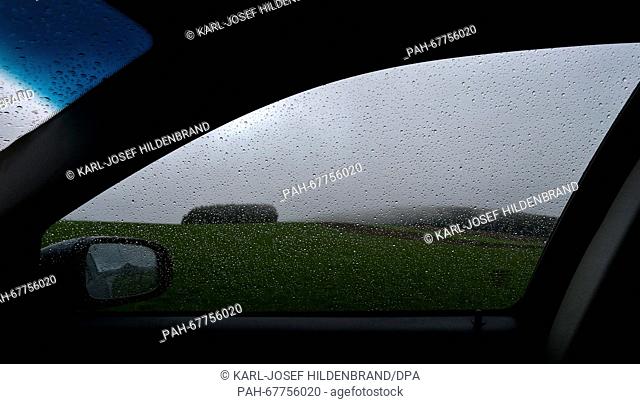 Dark clouds hovering above the Allgau landscape, pictured behind a car window covered by rain drops near Genachhausen, Germany, 17 April 2016