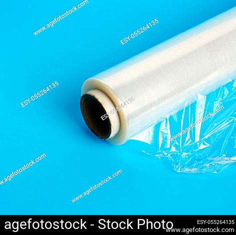 big roll of wound white transparent film for wrapping food, blue background, close up