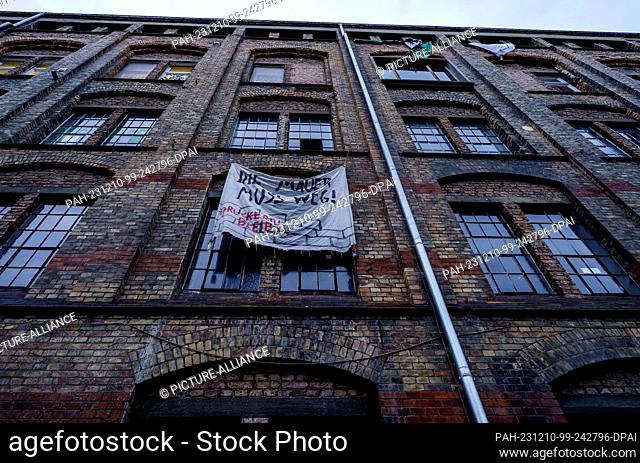 10 December 2023, Hesse, Frankfurt/Main: A banner ""The wall must go!"" hangs on the façade of the Dondorf print shop, which has been occupied again