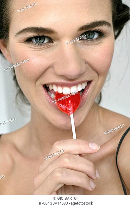 Portrait of young woman eating candy lollipop
