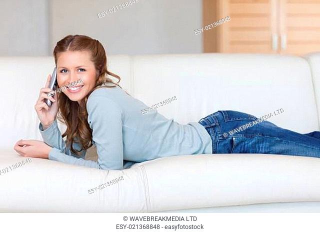 Cheerful smiling woman on the sofa with the phone