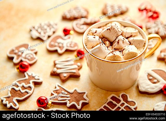 Cup of hot chocolate with tasety marshmellows. Fresh baked Christmas shaped gingerbread cookies on sides. With Xmas decorations. View from above