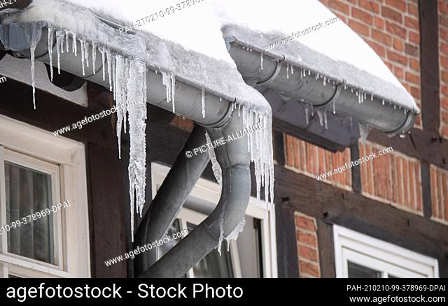 10 February 2021, Lower Saxony, Peine: Icicles hang from the roof of a house. Photo: Julian Stratenschulte/dpa. - Peine/Lower Saxony/Germany