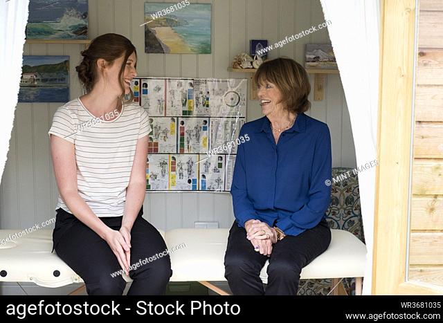 Woman and female therapist talking seated on a treatment couch