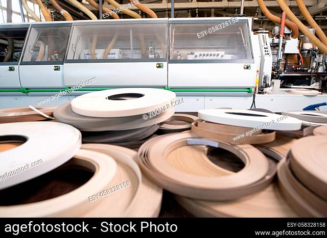 Pile of rolled up paper strips placed near industrial machinery in workshop of wooden furniture factory
